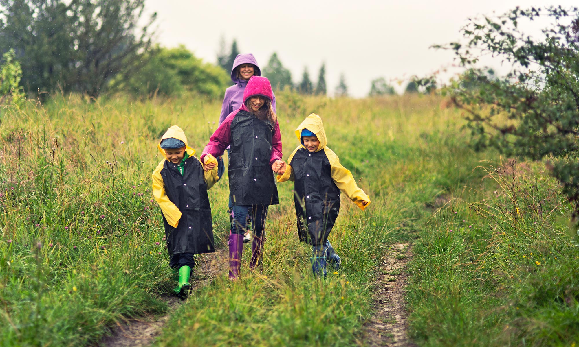 En familj med regnkläder ute i naturen