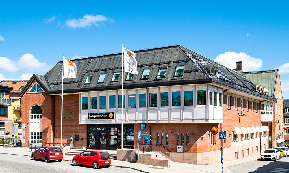 Tre personer står tätt tillsammans i en skogsmiljö. En vuxen håller om ett barn i mössa, medan ytterligare en vuxen står nära – en varm och trygg familjesituation utomhus.