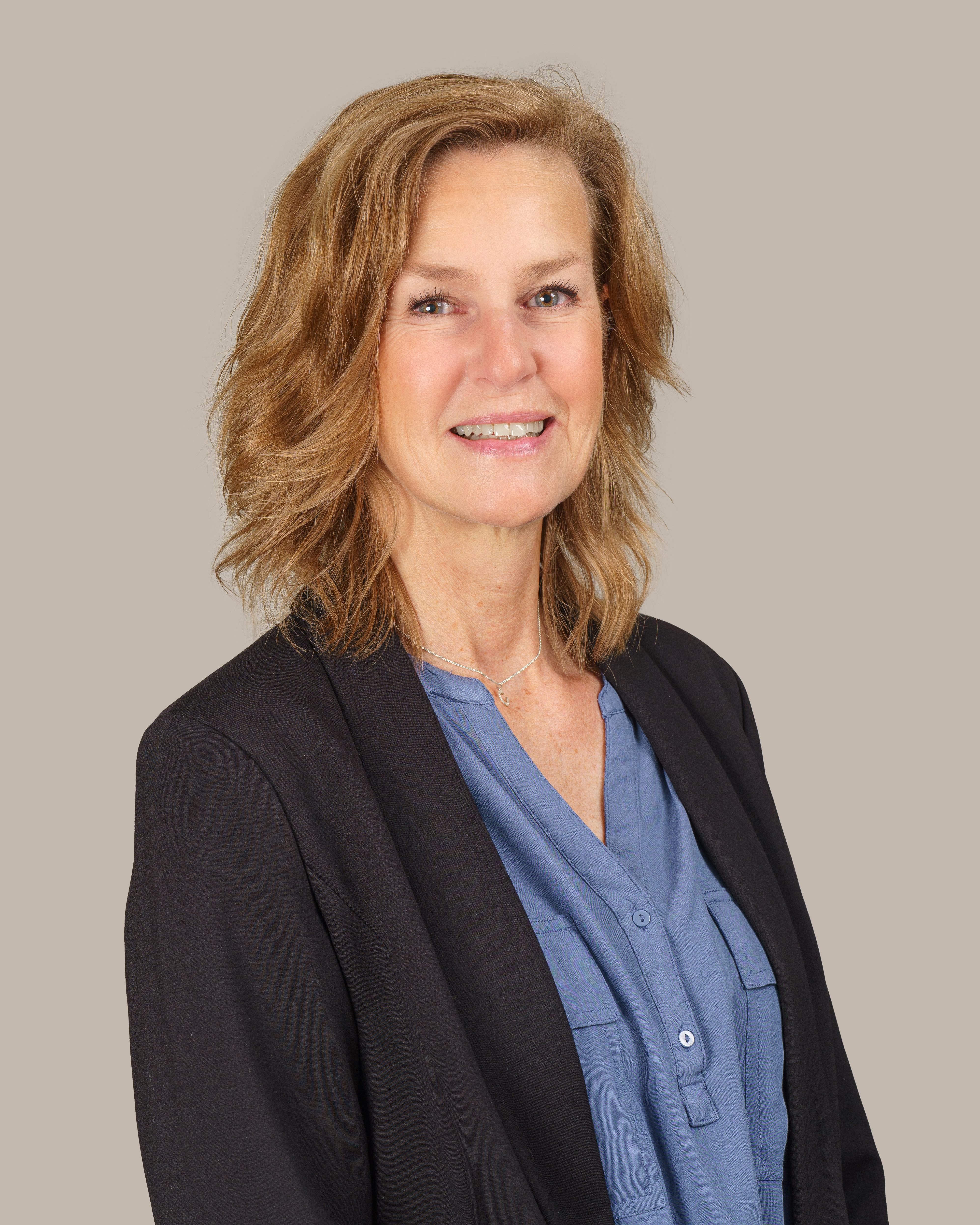 orträtt av en leende premiumrådgivare med axellångt ljusbrunt hår, blå blus och svart kavaj mot en ljus, neutral bakgrund